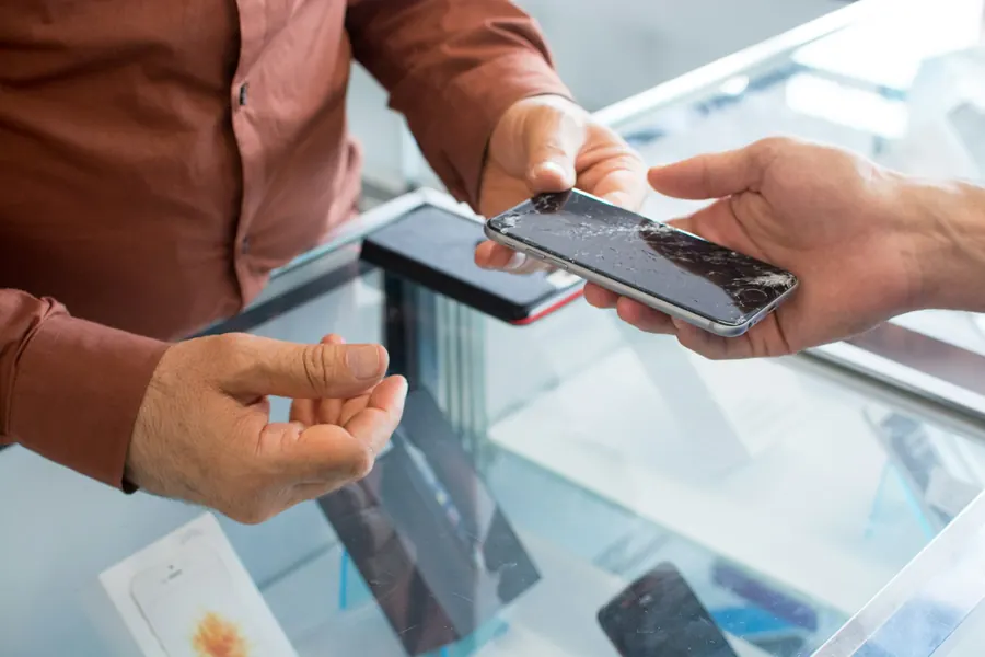 Cliente entregando o celular a um atendente no balcão